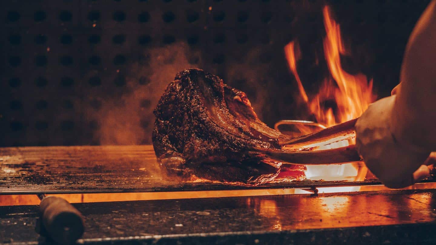 Person grilling meat on barbecue